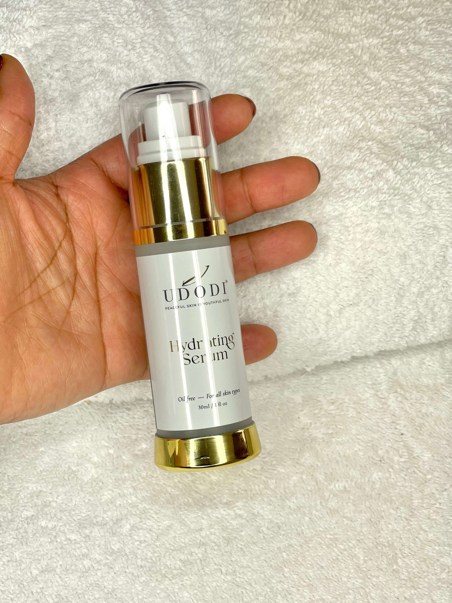 UDODI Hydrating Serum in a hand, providing anti-aging benefits while hydrating and protecting skin from environmental stress.